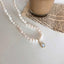Close-up of an elegant freshwater pearl necklace on a creamy backdrop, showcasing the unique iridescent pendant.