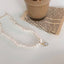 Close-up of an elegant freshwater pearl necklace on a creamy backdrop, showcasing the unique iridescent pendant.