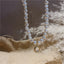 Close-up of an elegant freshwater pearl necklace on a creamy backdrop, showcasing the unique iridescent pendant.