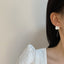 Delicate petal-shaped pearl drop earrings with a thin gold wire, reflecting artisanal elegance and natural charm.