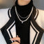 Dual-tone pearl necklace worn over a chic black turtleneck, embodying classic sophistication.